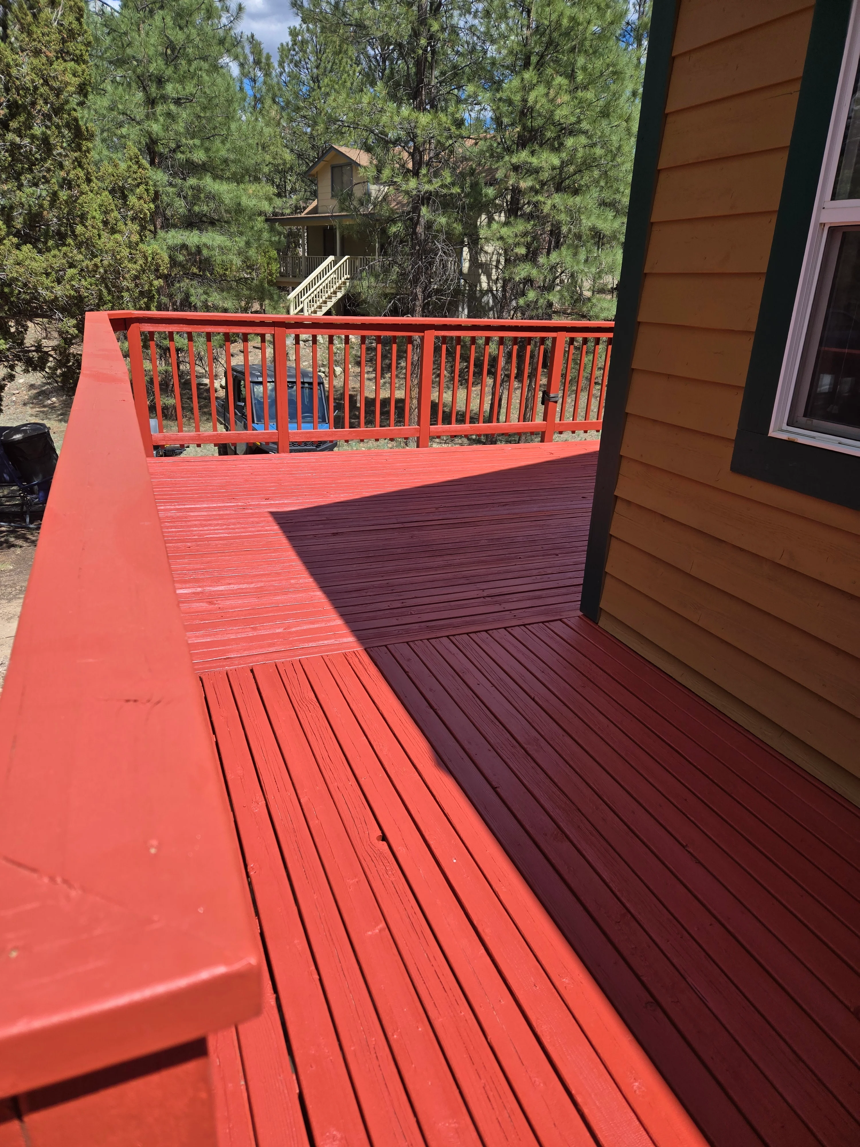 Two-tone deck with coral-red and burgundy stain, matching painted railings and fascia