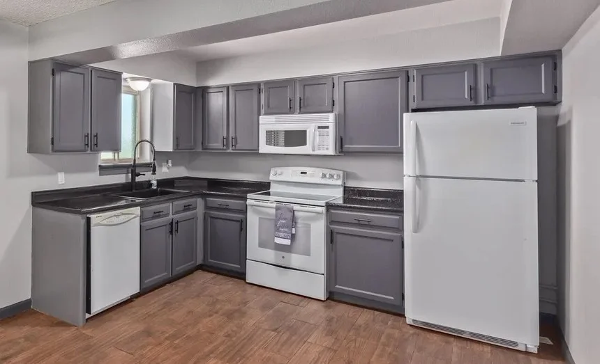 Gray painted kitchen cabinets with white appliances and black countertops