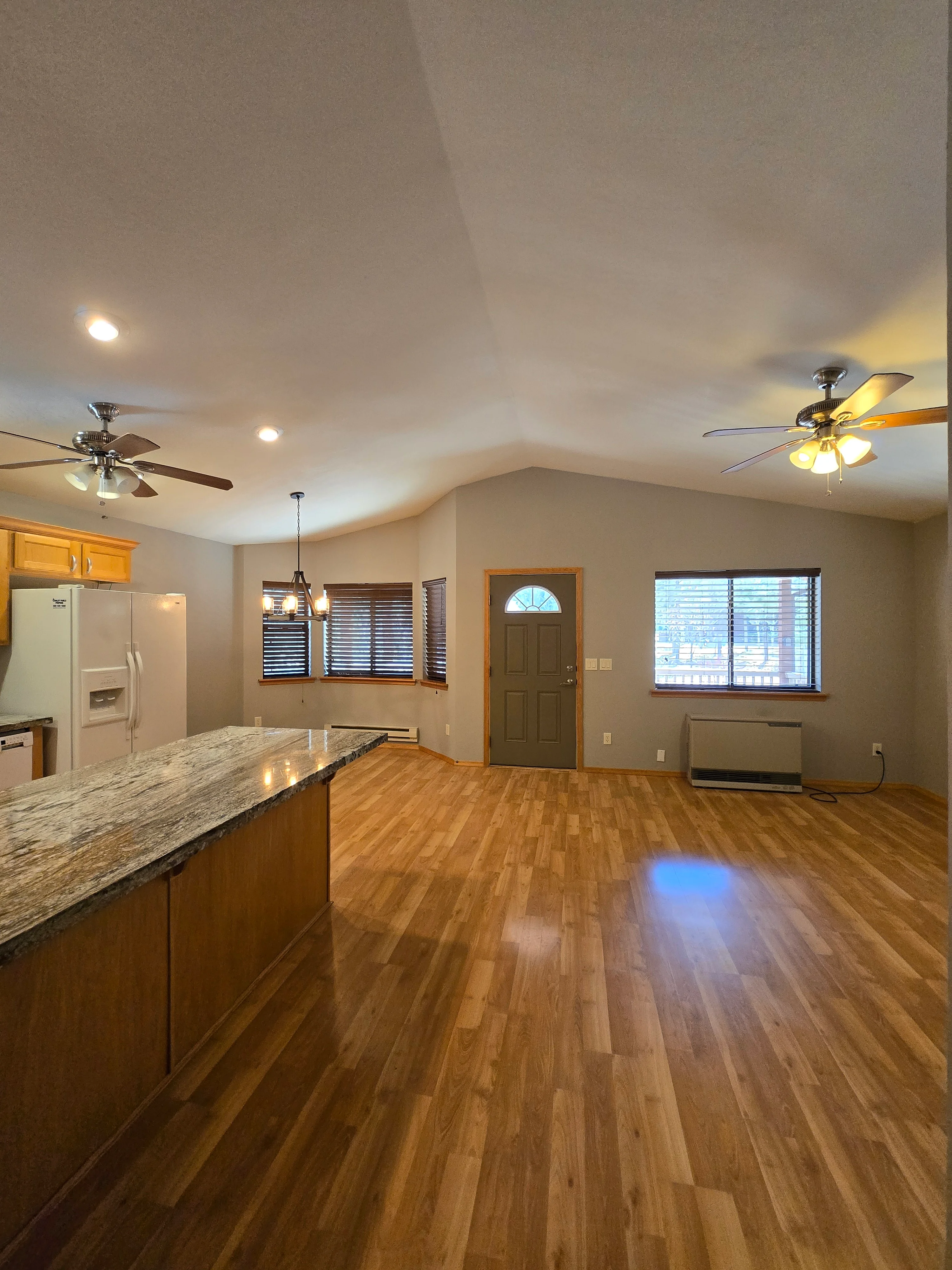 Interior kitchen and living room with taupe walls, white ceiling, recessed lights, and wood-look flooring