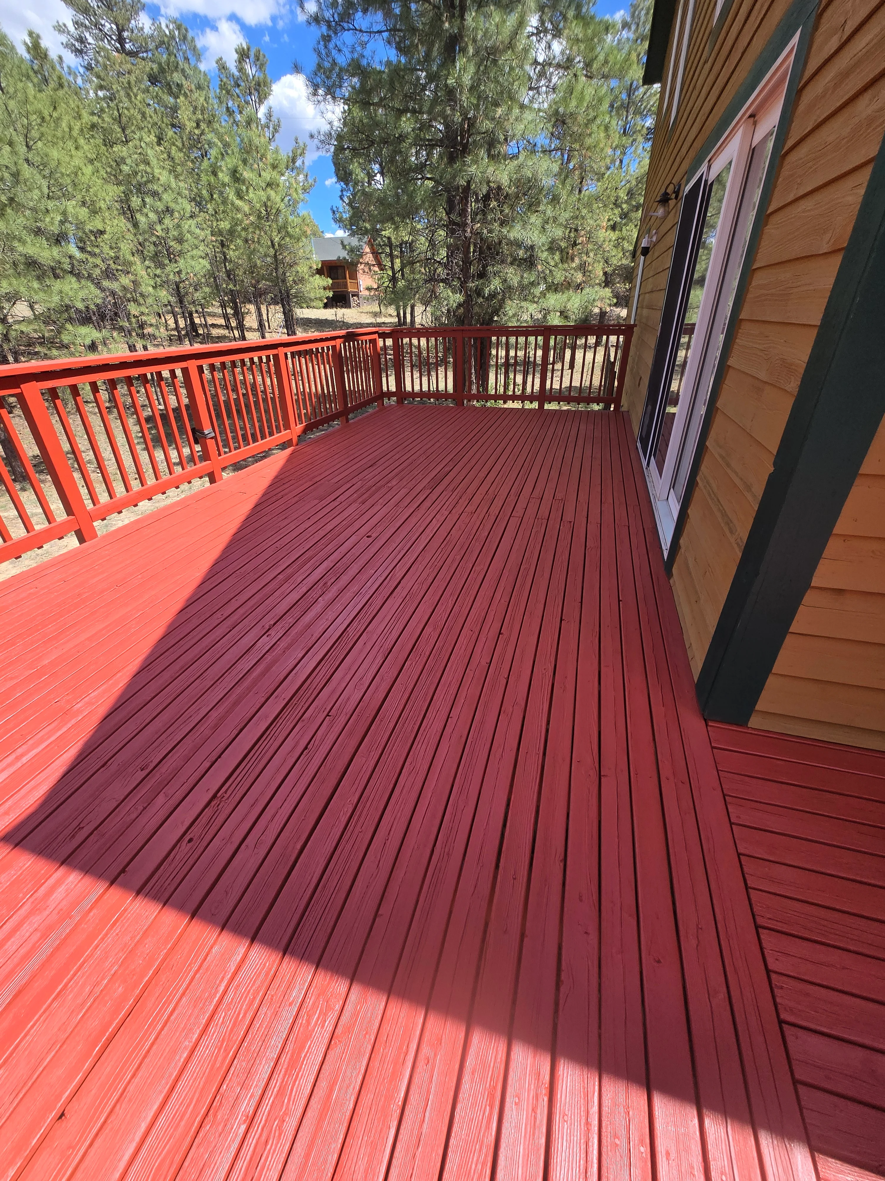 Burgundy-stained composite deck with matching railings and wood-tone siding trim