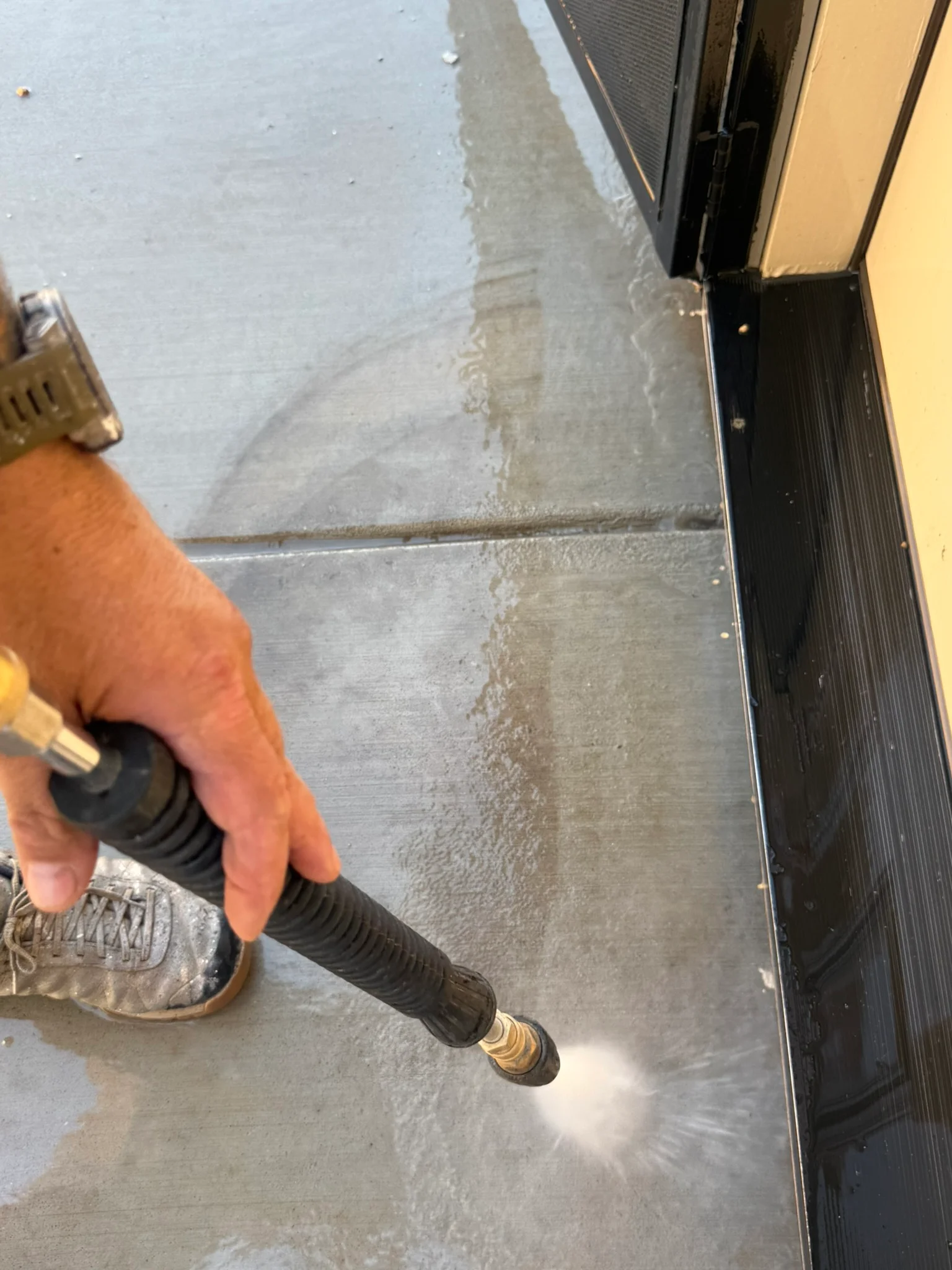 Pressure washing concrete floor with high-pressure nozzle, removing surface contaminants