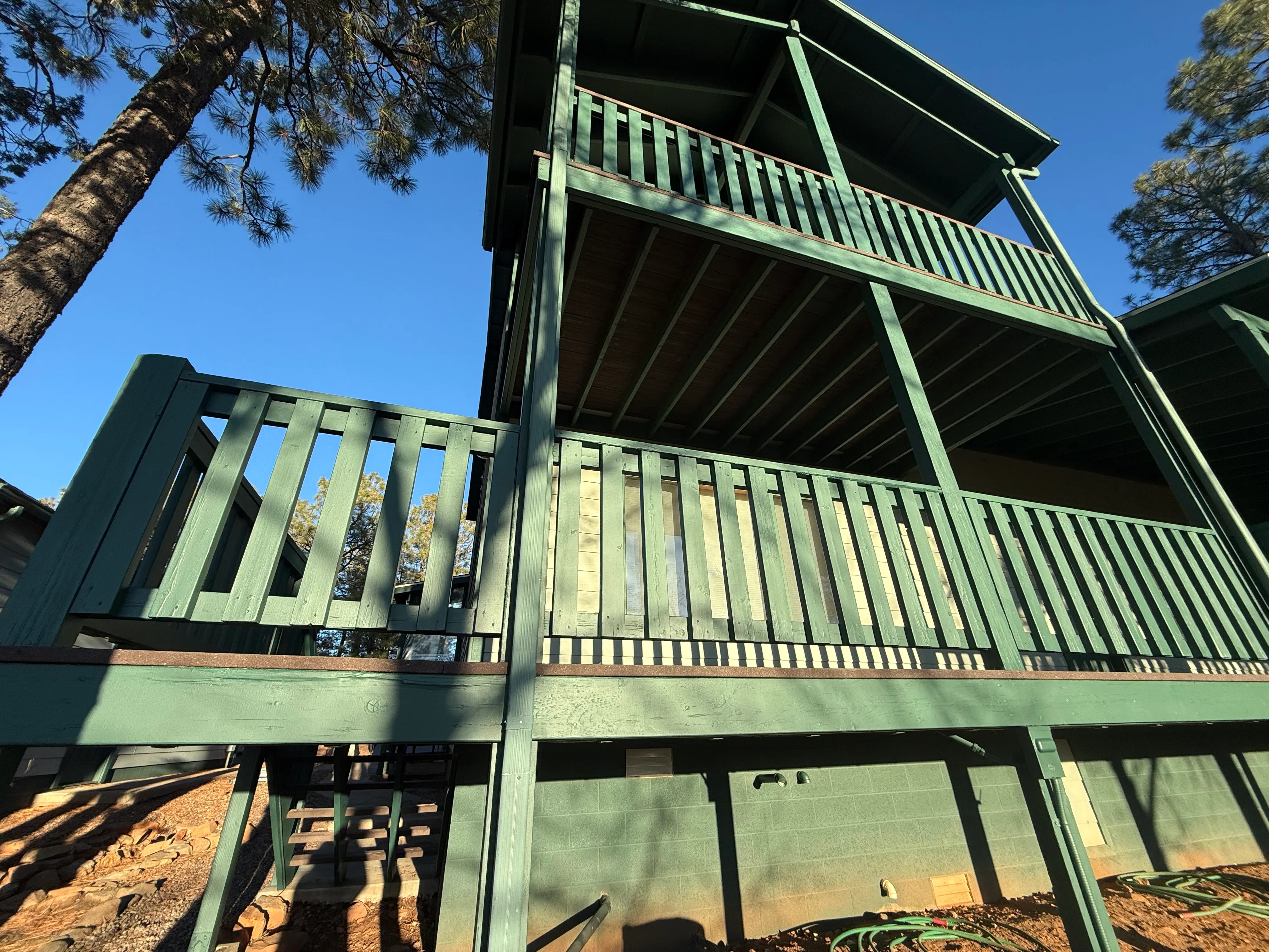 Green-stained elevated deck with vertical railings and exposed beam structure