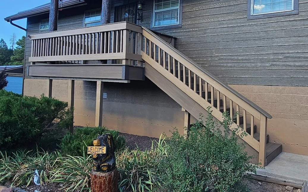 Tan-stained multi-level deck with vertical spindle railings and wooden stairs