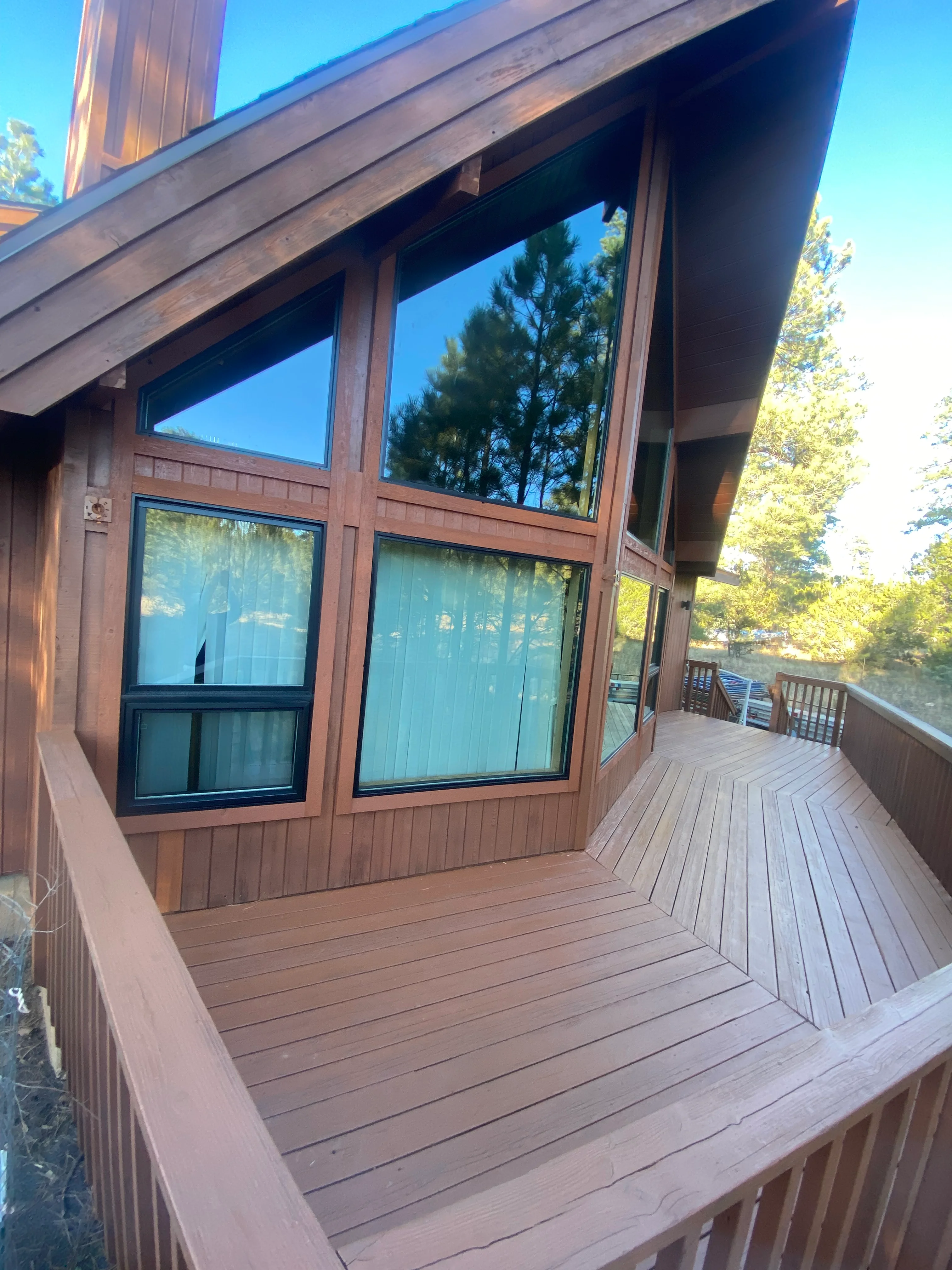 Newly stained composite deck with warm finish, glass doors and windows, wood railings