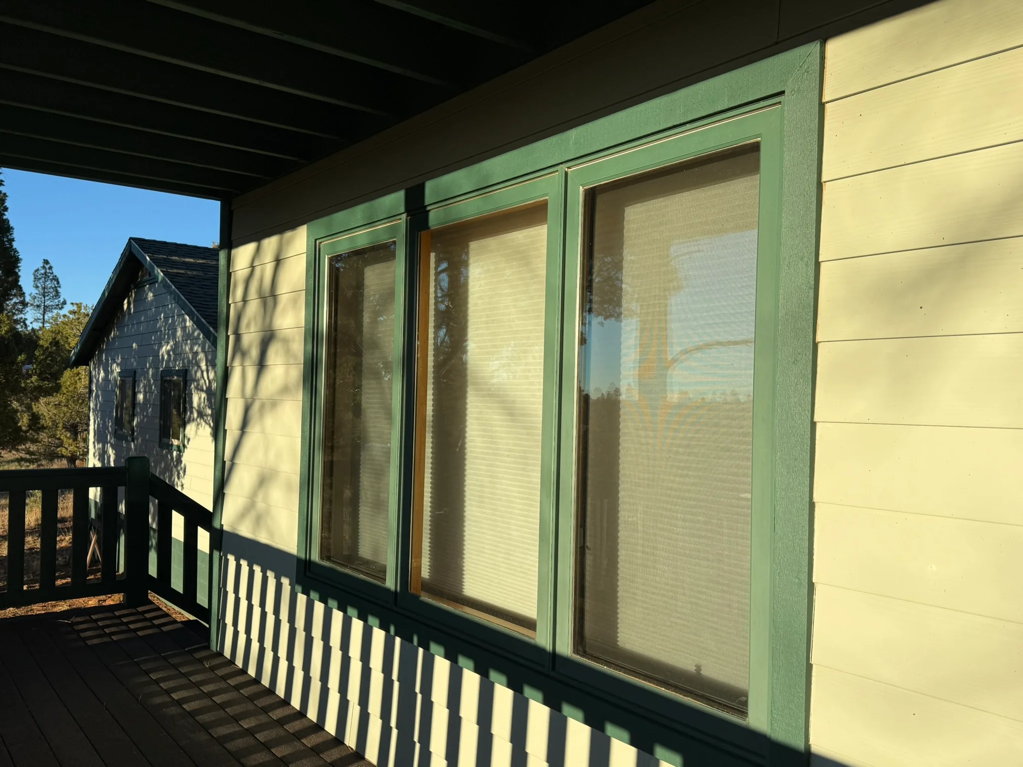 Yellow siding with green trim and three sliding glass doors on covered porch
