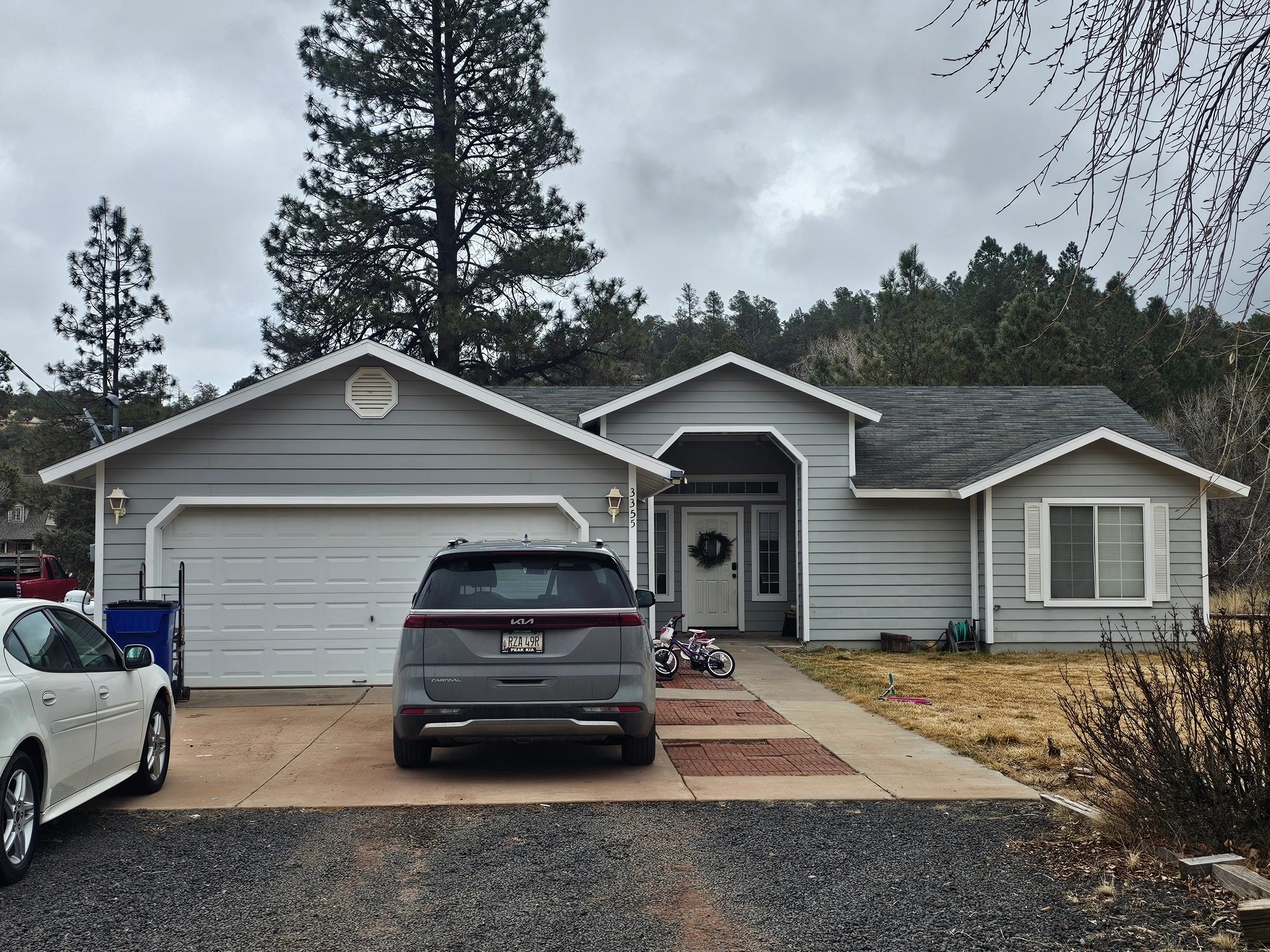 Gray house exterior with white trim, horizontal siding, white garage door, and landscaping