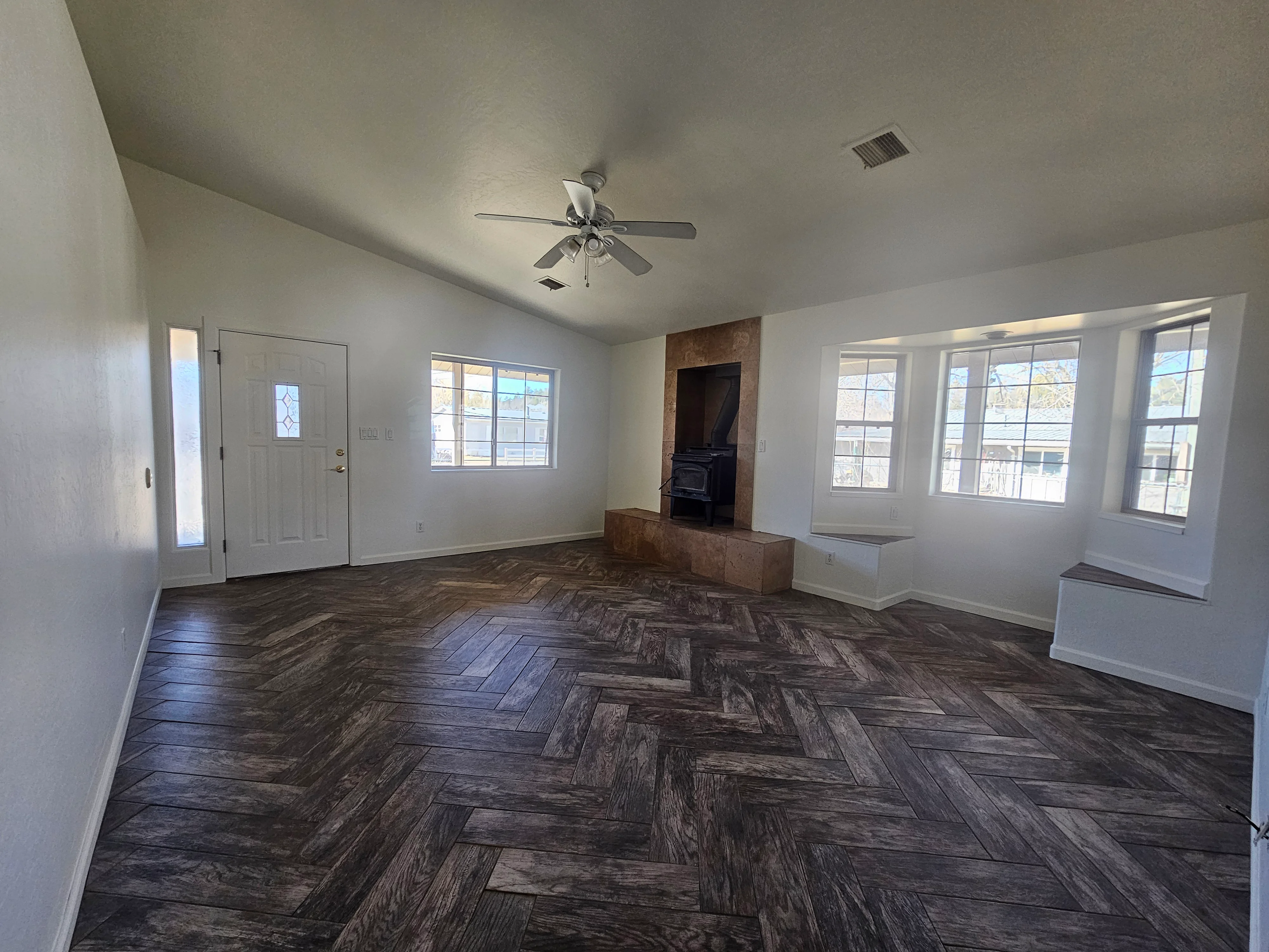 Freshly painted interior walls, ceiling, and white trim with herringbone wood flooring and brick fireplace