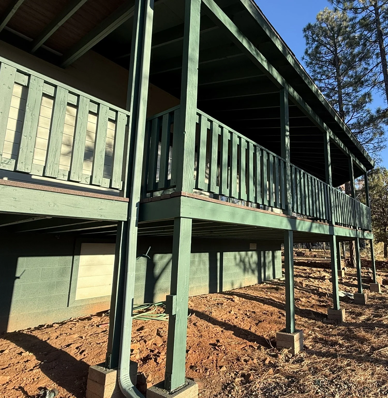 Green-painted wood house exterior with railings, trim, and multi-level deck structure