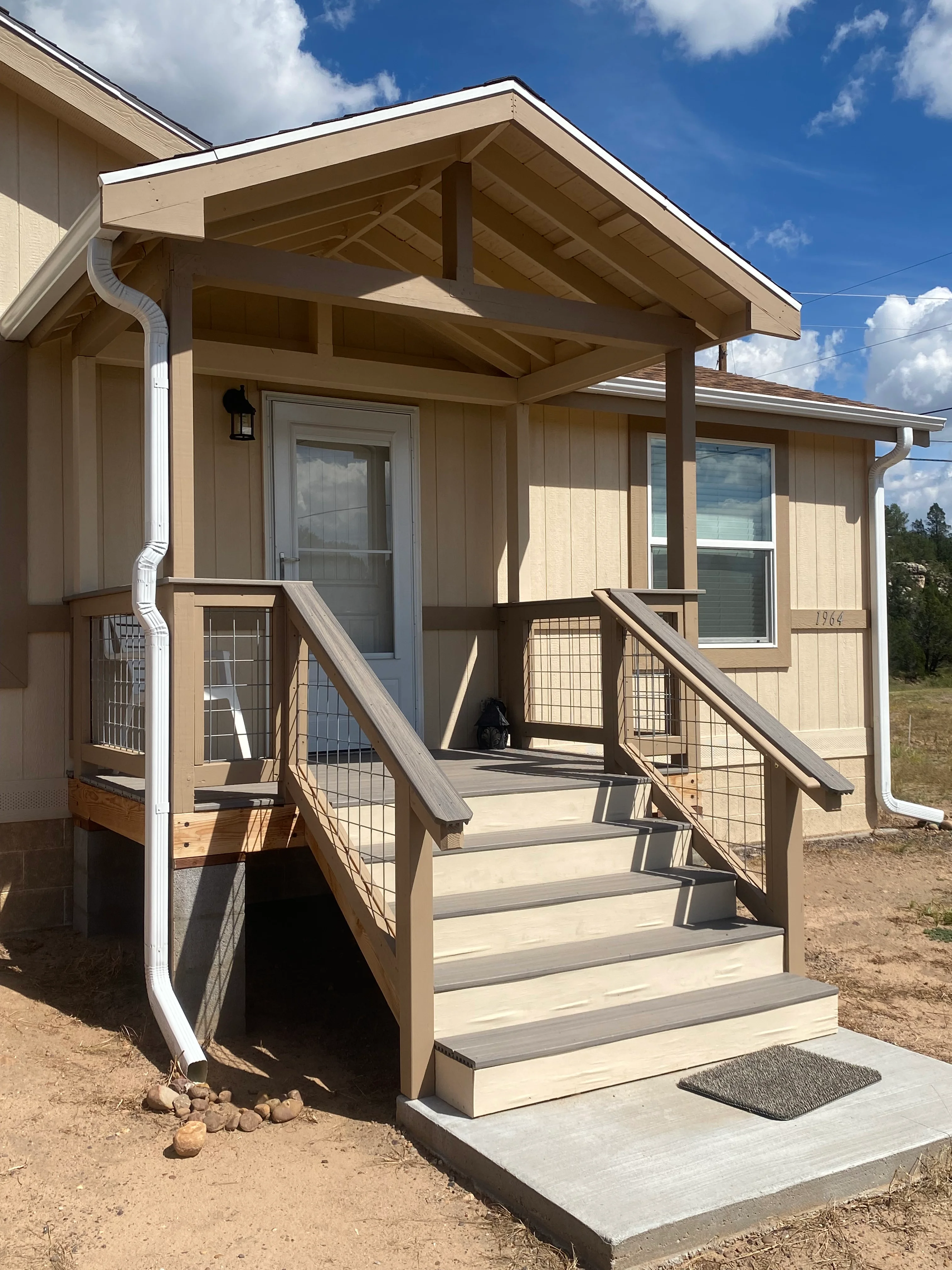Cream and tan painted cabin exterior with stained wood porch, railings, and steps