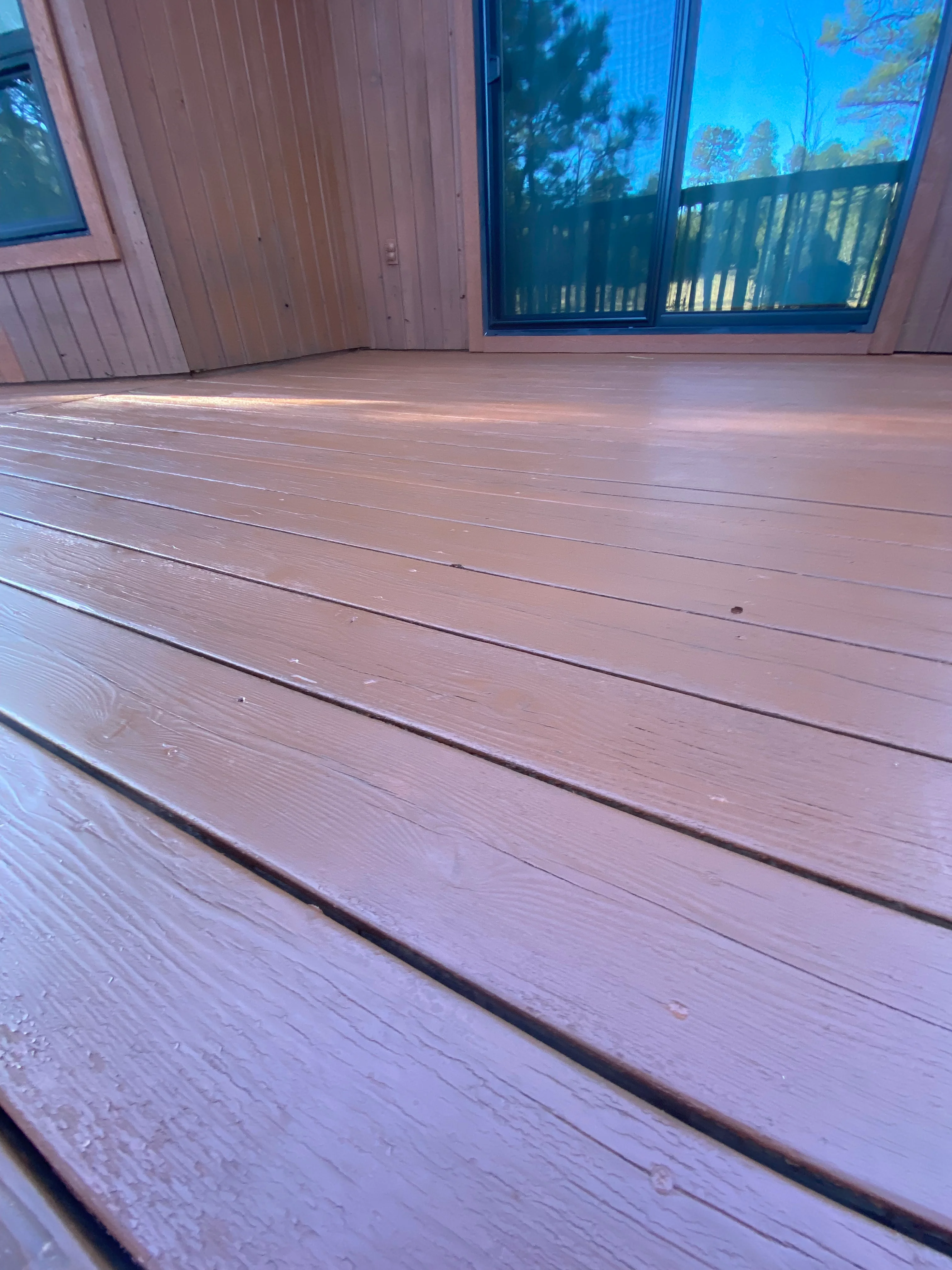Newly stained deck with mauve-brown finish, composite boards, sliding glass doors visible