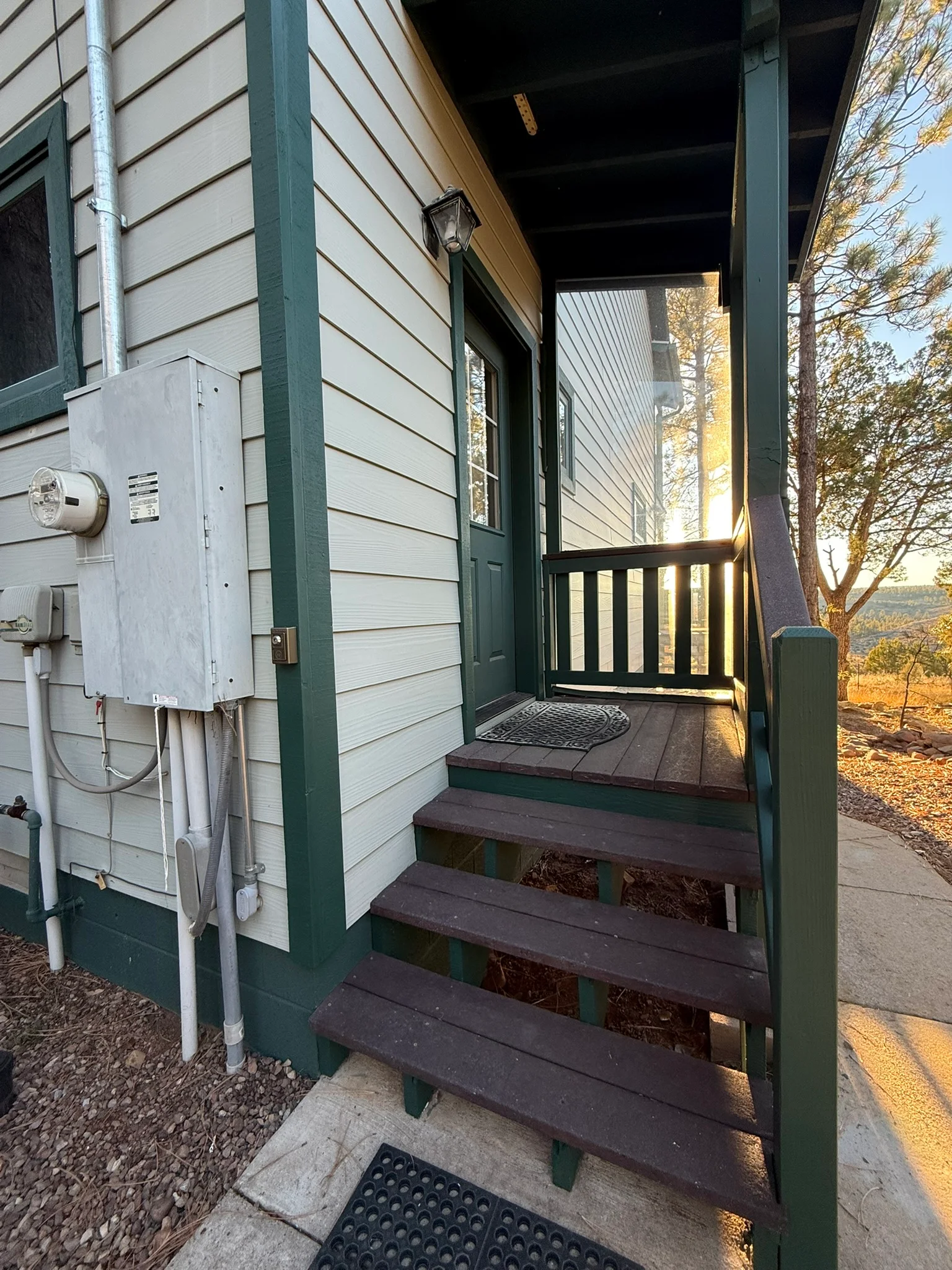 White horizontal siding with forest green trim, dark brown stained deck stairs and railings on residential porch entry