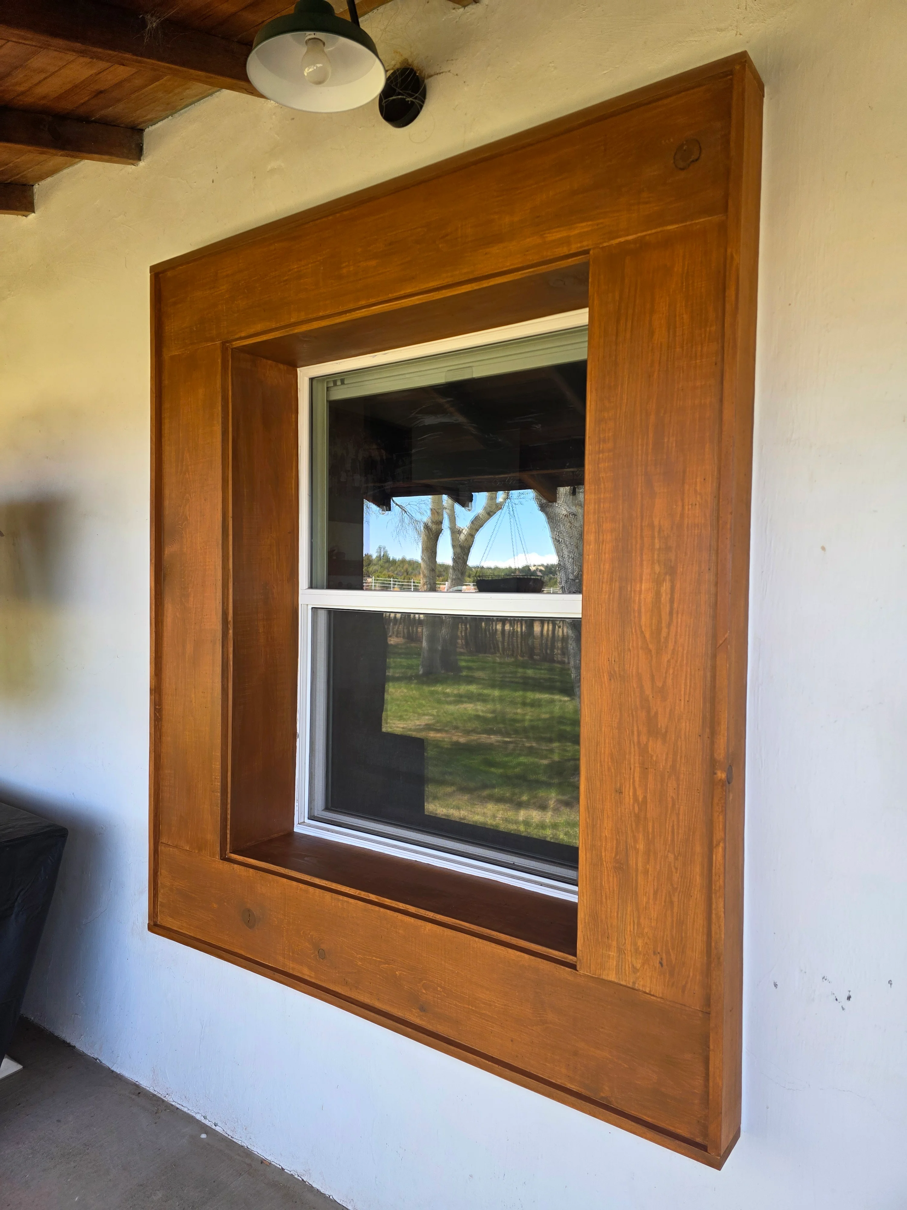 Stained wood window frame with white trim and double-pane glass in residential interior